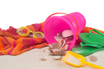 Fototapeta na wymiar Beach Still Life Scene with towel, bucket, and seashells on white sand background with room or space for copy. It's a horizontal photo with isolated on white.