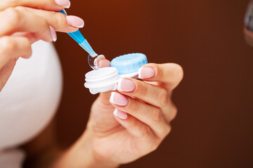 Woman removes contact lenses from a container with liquid