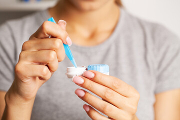 Woman removes contact lenses from a container with liquid