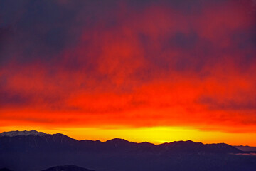 八ヶ岳北端、北横岳（標高 2480m）から望む、マジックアワーに真っ赤に色づいた夕焼け空の雲と山並み。The red clouds  in the west of magic hour and the mountain range from Yatsugatake mountain range.