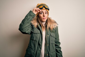 Young brunette skier woman wearing snow clothes and ski goggles over white background worried and stressed about a problem with hand on forehead, nervous and anxious for crisis