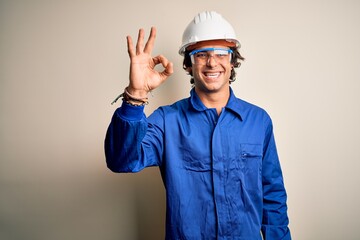 Young constructor man wearing uniform and security helmet over isolated white background smiling...