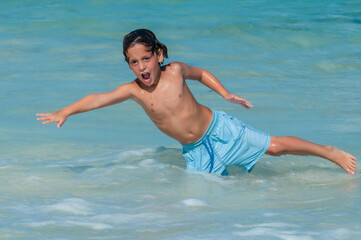 Niño se deja caer en el agua mientras juega en playa del Caribe Mexicano