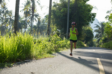 Young fitness woman running o tropical forest trail