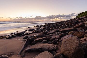 Obraz premium Big rocks around the beach coastline with cloudy sky.