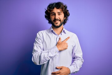 Young handsome business man with beard wearing shirt standing over purple background cheerful with a smile on face pointing with hand and finger up to the side with happy and natural expression