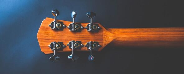 Acoustic guitar, music instrument resting against a dark black background with copy space, Close-up...