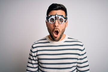 Young handsome man with beard wearing optometry glasses over isolated white background afraid and shocked with surprise expression, fear and excited face.