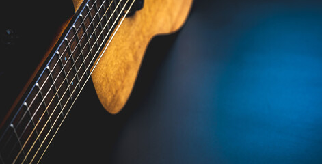 Acoustic guitar, music instrument resting against a dark black background with copy space, Close-up of wooden classic guitar