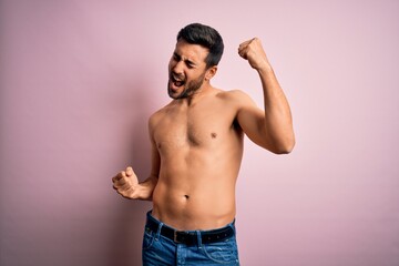 Fototapeta premium Young handsome strong man with beard shirtless standing over isolated pink background Dancing happy and cheerful, smiling moving casual and confident listening to music