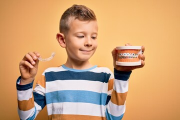 Little kid boy holding professional orthodontic denture with metal braces and removable invisible...