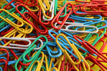A pile of paperclips of different colours used in stationary to affix various pieces of paper together.