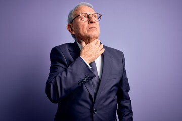 Grey haired senior business man wearing glasses and elegant suit and tie over purple background Touching painful neck, sore throat for flu, clod and infection