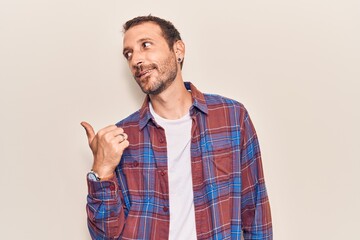 Fototapeta premium Young handsome man wearing casual clothes smiling with happy face looking and pointing to the side with thumb up.