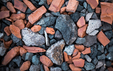 Background with different size and colour rocks and bricks on the ground.