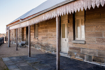 Historic Australian sandstone brick cottage exterior with verandah patio, corrugated iron roof