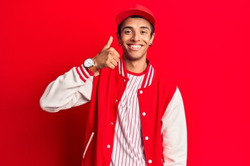 Young african amercian man wearing baseball uniform smiling happy and positive, thumb up doing excellent and approval sign
