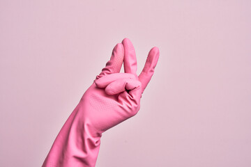 Hand of caucasian young man with cleaning glove over isolated pink background snapping fingers for...