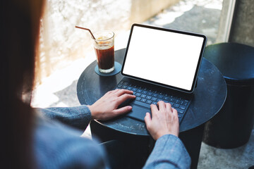 Mockup image of a woman using and typing on tablet keyboard with blank white desktop screen as computer pc with coffee cup on the table