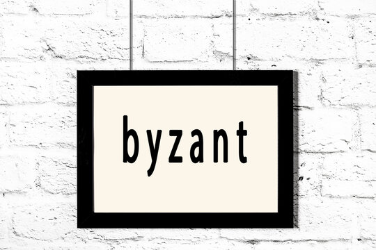 Black frame hanging on white brick wall with inscription byzant