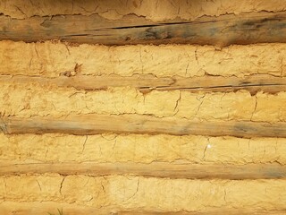 orange dried mud or adobe wall with wood