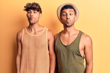 Young gay couple wearing summer clothes making fish face with lips, crazy and comical gesture. funny expression.