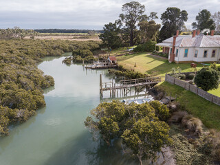 Naklejka premium Aerial drone shot of a residential house and fishing boat moored at the jetty in the coastal town Tooradin.
