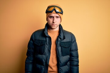 Young handsome caucasian man wearing hat, coat and ski glasses for winter and snow weather skeptic and nervous, frowning upset because of problem. Negative person.