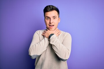Young handsome caucasian man wearing casual sweater over purple isolated background shouting and suffocate because painful strangle. Health problem. Asphyxiate and suicide concept.