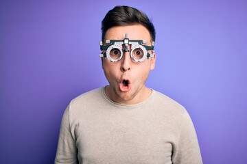 Obraz premium Young handsome caucasian man wearing optometrical glasses over purple background afraid and shocked with surprise expression, fear and excited face.