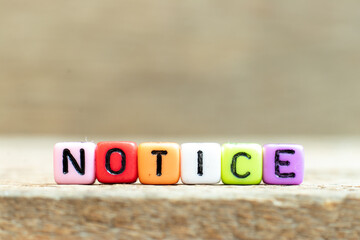 Colorful bead with black letter in word notice on wood background