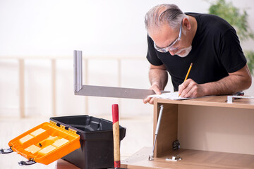 Old male carpenter working indoors