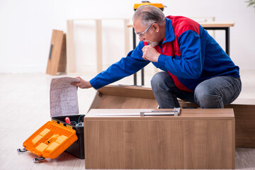 Old male carpenter working indoors
