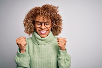 Young beautiful african american woman wearing turtleneck sweater and glasses excited for success...