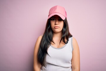 Fototapeta premium Young brunette woman wearing casual sport cap over pink background depressed and worry for distress, crying angry and afraid. Sad expression.