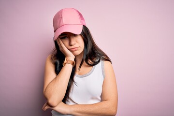 Young brunette woman wearing casual sport cap over pink background thinking looking tired and bored with depression problems with crossed arms.