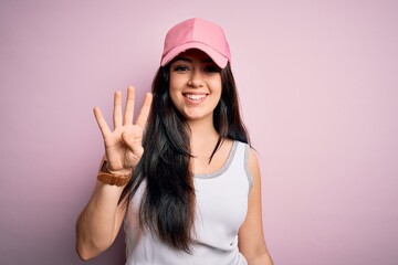 Obraz na płótnie Canvas Young brunette woman wearing casual sport cap over pink background showing and pointing up with fingers number four while smiling confident and happy.