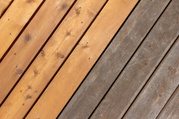 Close up abstract texture background of a cedar wood deck floor with a diagonal layout design, showing new boards alongside older weathered boards, with copy space