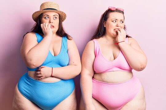 Young plus size twins wearing bikini looking stressed and nervous with hands on mouth biting nails. anxiety problem.