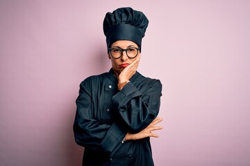 Middle age brunette chef woman wearing cooker uniform and hat over isolated pink background thinking looking tired and bored with depression problems with crossed arms.
