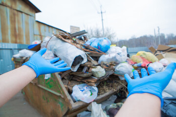 a man in rubber gloves points to a pile of garbage in a container. garbage collapse. Janitors '...