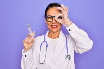 Middle age senior professional doctor woman holding syringe with medical vaccine with happy face...