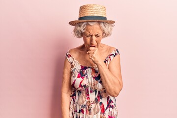 Senior grey-haired woman wearing summer hat feeling unwell and coughing as symptom for cold or...