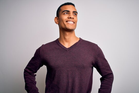 Young handsome african american man wearing casual sweater over white background looking away to side with smile on face, natural expression. Laughing confident.