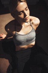 Naklejka premium Caucasian blonde fitness lady resting after doing home sport exercises on the floor