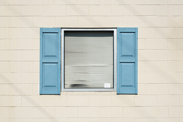 Window with blue shutters opened on a white wall