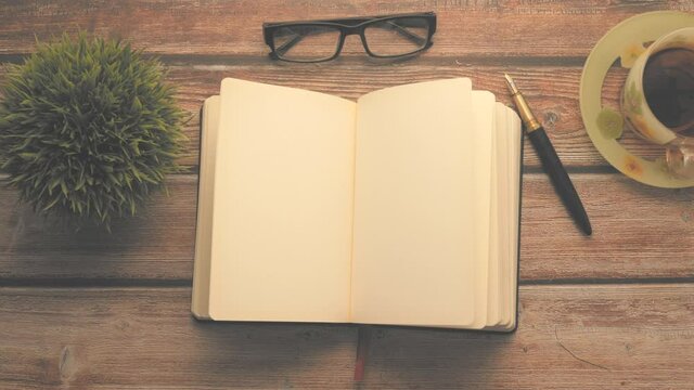 high angle view of open diary, tea and eyeglass on wooden table 