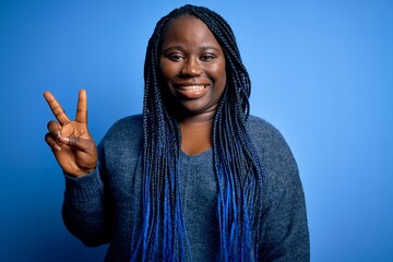 African american plus size woman with braids wearing casual sweater over blue background showing and pointing up with fingers number two while smiling confident and happy.