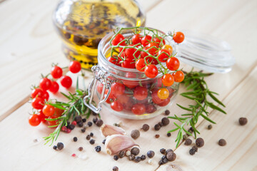 tomatoes in a jar, rosemary and garlic on a wooden background, selective focus
