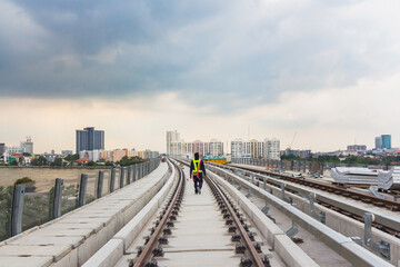 Inspector (Engineer) checking railway construction work on skytrain viaduct. Which railway consist of rail track and conductor rail or third rail.